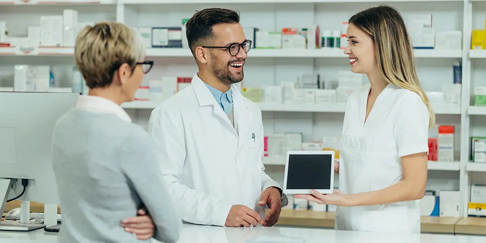 Pharmacists giving prescription medications to a customer. Solving vendor fatigue in the pharmaceutical industry.