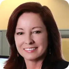 Professional headshot of Mary-Ann, a smiling woman with auburn hair and a business-casual outfit.