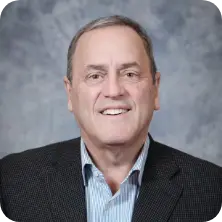 Professional headshot of Richard, smiling. Man in suit and blue shirt. Business portrait.